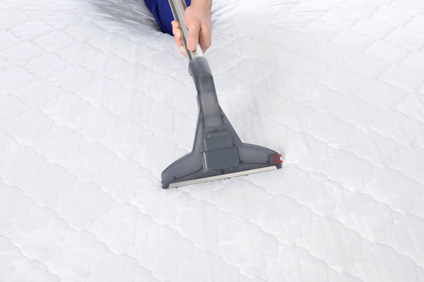 Man disinfecting mattress with vacuum cleaner, closeup - Valokuva, kuva