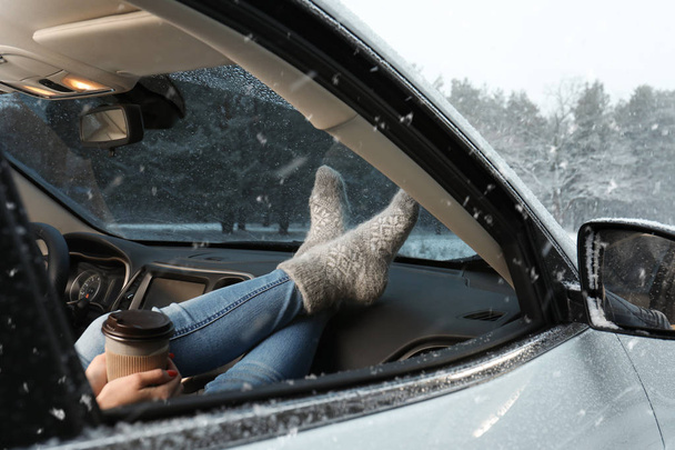 Young woman in warm socks resting inside car, closeup - Foto, afbeelding