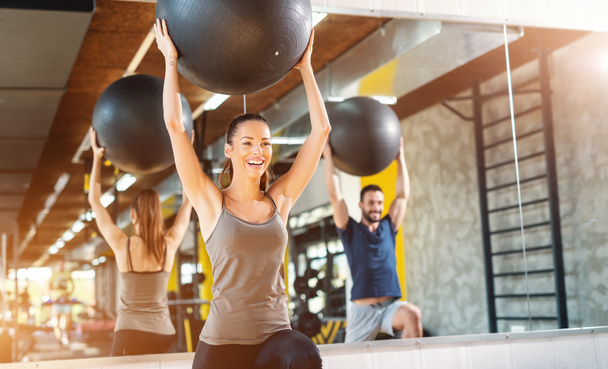 Smiling happy Caucasian Couple in sportswear doing pilates exercises in gym. - Photo, Image