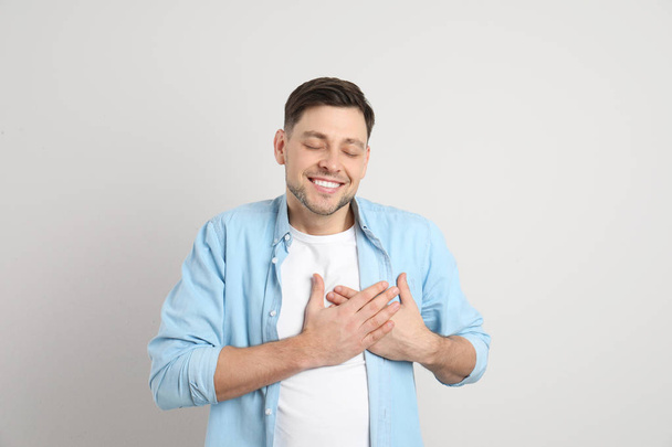 Miehen muotokuva kädestä lähellä sydäntä kevyellä taustalla
 - Valokuva, kuva