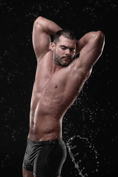 Shirtless handsome young man posing with water splashes on face and chest in Studio shot - Valokuva, kuva