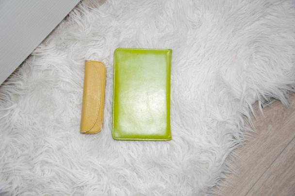zielony ebook lub tabletu w skóry pokrywa ze szkła, niosąc pudełko lub żółty kolor koperty na dywanie białe futro, zbliżenie, miejsce - Zdjęcie, obraz