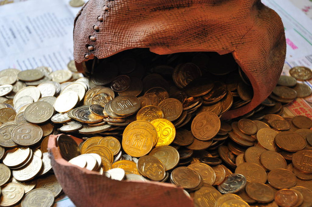 Oekraïens munten gouden of goud kleur in heap in de buurt van gebroken keramische moneybox zoals de besparingen symbool achtergrond - Foto, afbeelding