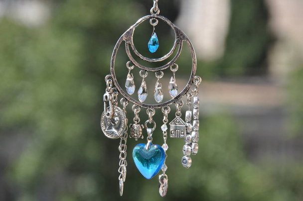 Magical power. Name amulet for good luck. Silver amulet with gems and pendants. Luck amulet hung out outdoor. Believing in magic protecting the holder of amulet. Jewelry charm or talisman. - Photo, Image
