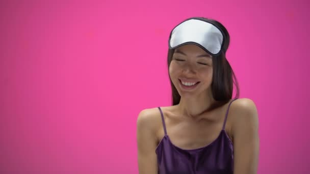 Young Asian woman flirting and wearing eye mask, isolated on pink background - Filmati, video