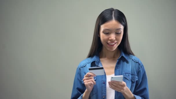 Attractive woman entering credit card number on smartphone, shopping online - Filmagem, Vídeo