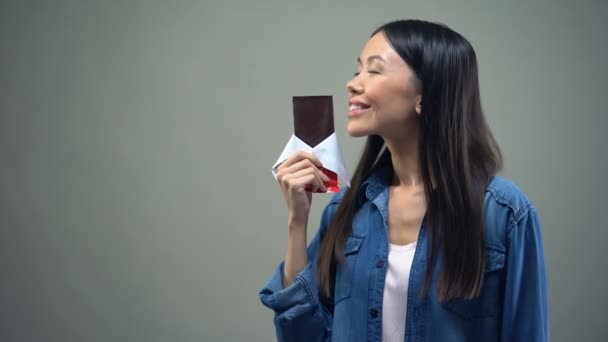 Funny girl enjoying sweet aroma of chocolate bar, kissing it, woman keeping diet - Кадри, відео
