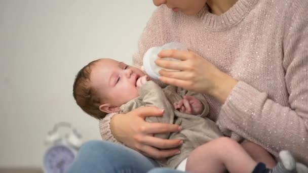 Mladá maminka malého chlapečka krmení z láhve, umělé kojenecké výživy krmení - Záběry, video