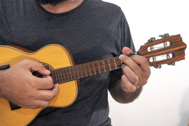 Young man playing ukulele with shirt and black pants on white background - Fotó, kép