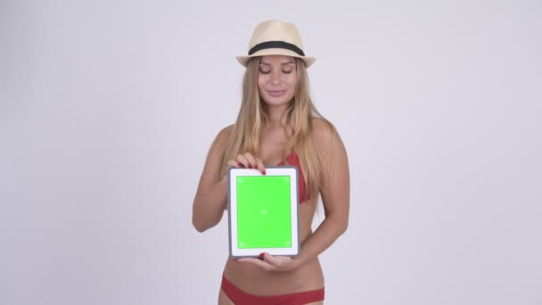 Happy young blonde tourist woman thinking while showing digital tablet - Materiał filmowy, wideo