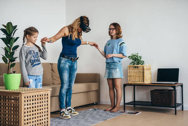 Donna che utilizza occhiali VR realtà virtuale a casa in piedi sul soggiorno con i bambini
. - Foto, immagini