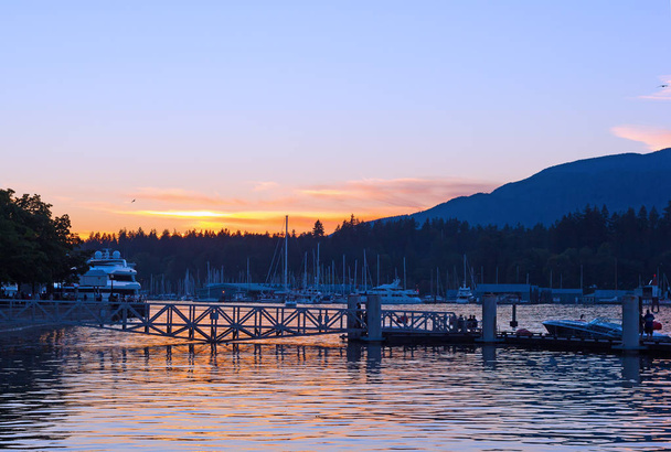 Vancouver Harbor with moored vessels at sunset, Vancouver BC, Canada. Beautiful sunset with clear skies and mountains on horizon. - Foto, afbeelding