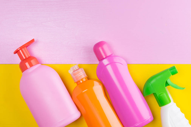δύο πολύχρωμα φόντα, κίτρινο και ροζ μαζί με μια σειρά από φιάλες από υγρά καθαρισμού - Φωτογραφία, εικόνα