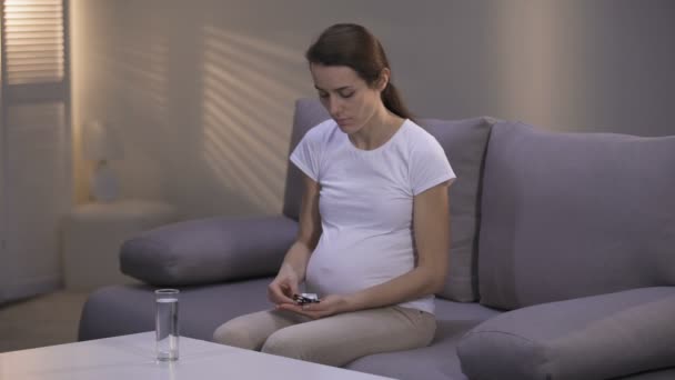Depressed pregnant woman taking pill, domestic violence victim in rehab, poverty - Filmati, video
