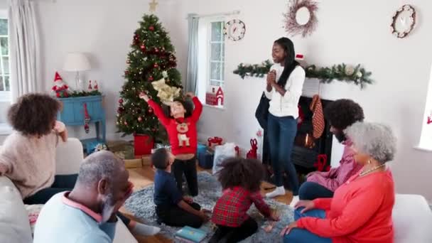 Children throwing wrapping paper into the air as they unwraping gifts at multi-generation Christmas celebration - shot in slow motion - Felvétel, videó