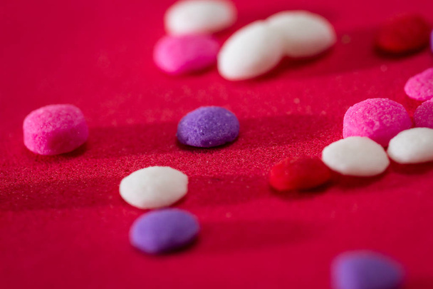 macro of a group of small edible sugar sprinkles in different hades of reds and white a valentines decorations background - Photo, Image