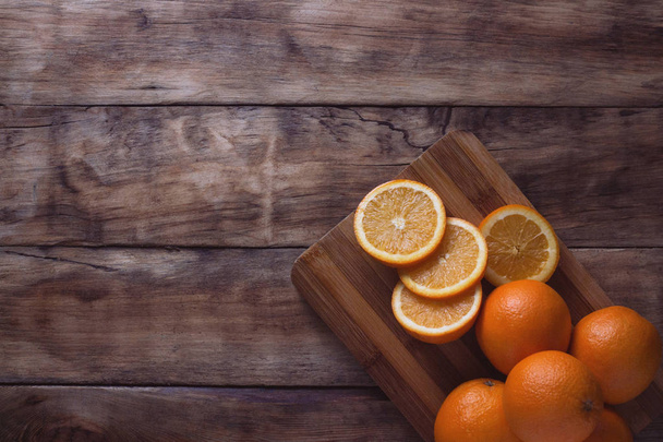 Κόψτε πορτοκαλιού, φέτες Apelsin στο ξύλινο ταμπλό. Σκούρο φόντο. Επίπεδη lay, κορυφαία προβολή. - Φωτογραφία, εικόνα