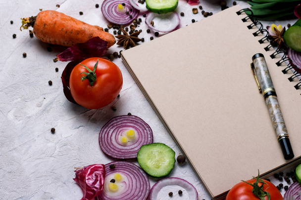 Jegyzetfüzet, toll, vágódeszka és zöldségek, a világos háttér. A koncepció a főzés, vegetáriánus és egészséges táplálkozás. - Fotó, kép