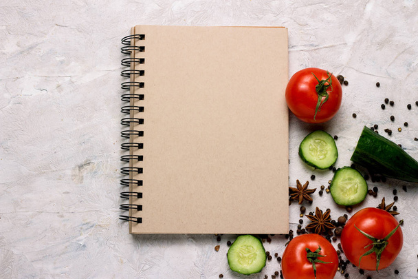 新鮮な野菜、トマト、きゅうり、スパイス、明るい背景に料理のレシピのメモ帳。料理は、菜食主義と健康的な食事の概念. - 写真・画像