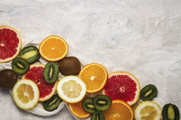 Fresh Fruits, Grapefruit, Lemon, Orange, Kiwi on a Light Stone background. Copy space and a top view. - Photo, Image