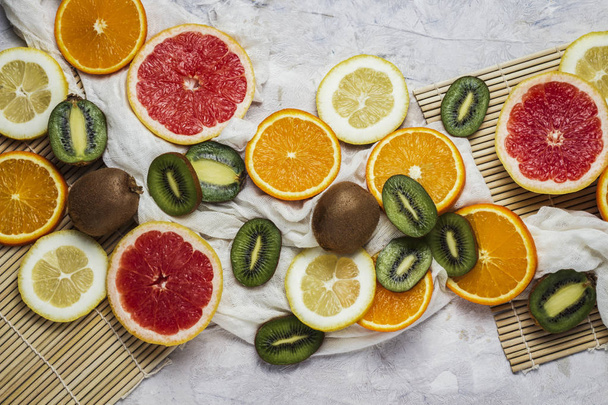 Čerstvé tropické ovoce, Grapefruit, citron, pomeranč, Kiwi na světlém pozadí kamene. Prostor a pohled shora. - Fotografie, Obrázek