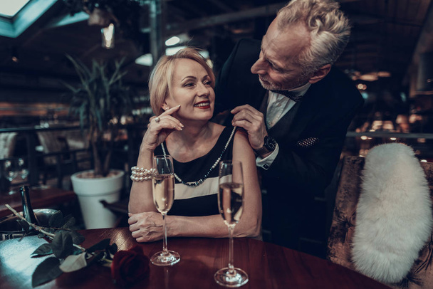 Businesswoman and Businessman . Old Business People .Successful Old People. Relax together. Romantic Meeting, Rich People. Couple Resting in Restaurant. Man gives necklace to woman. - Фото, изображение