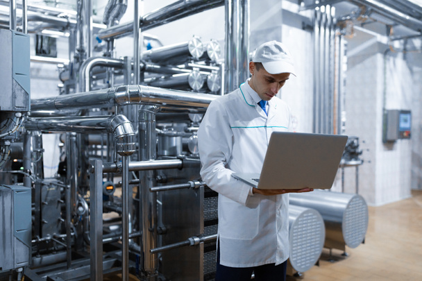 Technologue avec un ordinateur portable dans ses mains à l'usine laitière
 - Photo, image