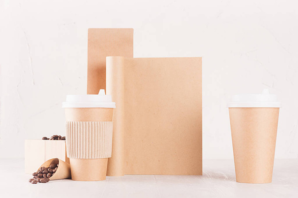 Coffee branding identity mockup in minimalist style - kraft brown paper packing, cups and blank notebook with coffee beans on white wooden background. - Фото, зображення