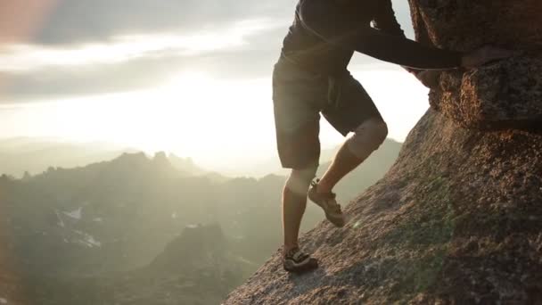 Egy ember, egy szikla mászás napnyugtakor lábak. - Felvétel, videó