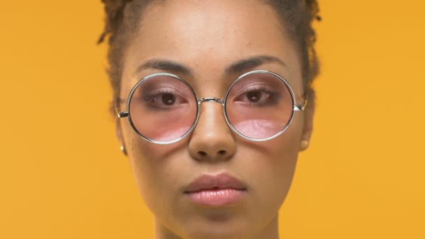 Young african woman taking off eyeglasses looking shocked on camera, dermatology - Filmati, video