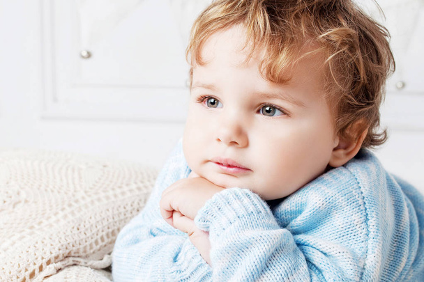 Portrait of happy adorable baby boy on the bed in his room. Thoughtful look. Copy space - Foto, Imagem