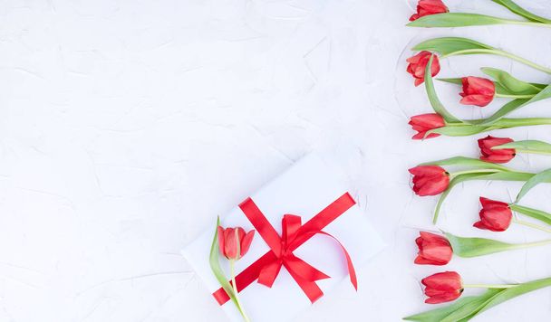 A bouquet of red tulips and a box with a bow on a white backgrou - Fotografie, Obrázek