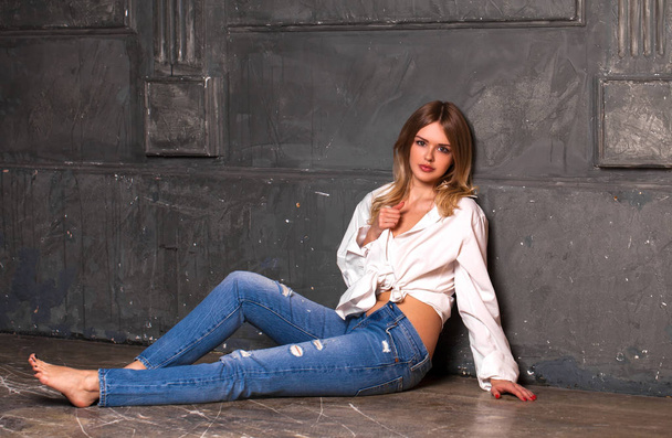 Fashion shoot of young sexy woman in blue jeans and white shirt in dark studio - Foto, immagini