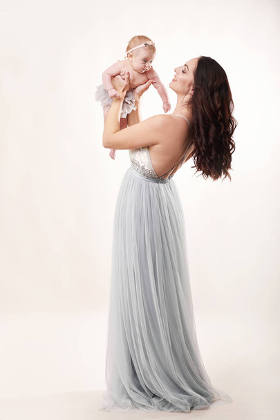 jonge aantrekkelijke moeder met een klein meisje op een lichte achtergrond - Foto, afbeelding