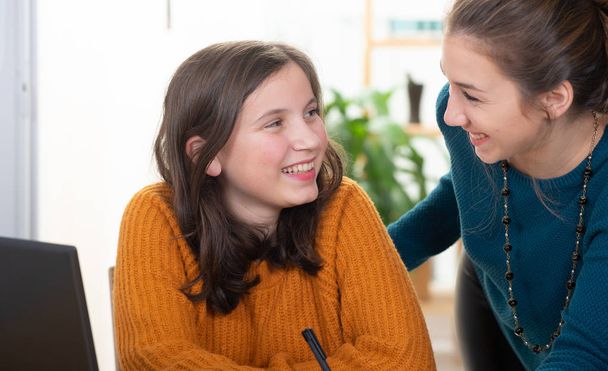 jovem mulher ajuda uma menina adolescente com lição de casa
 - Foto, Imagem