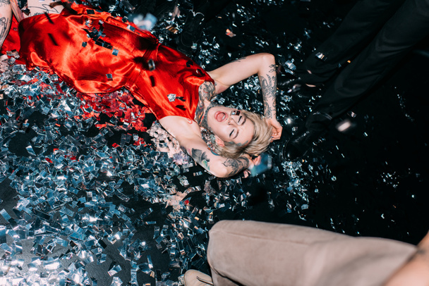 opilá žena ležící na podlaze s konfety u lidí na party, samostatný na černém - Fotografie, Obrázek