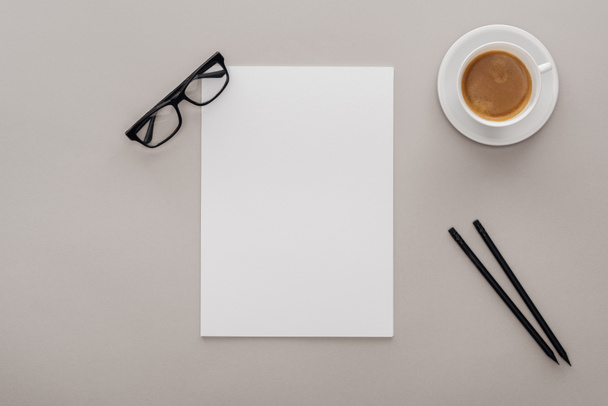 vue du dessus des lunettes noires, crayons et papier blanc vide sur le lieu de travail avec une tasse de café sur fond gris
 - Photo, image
