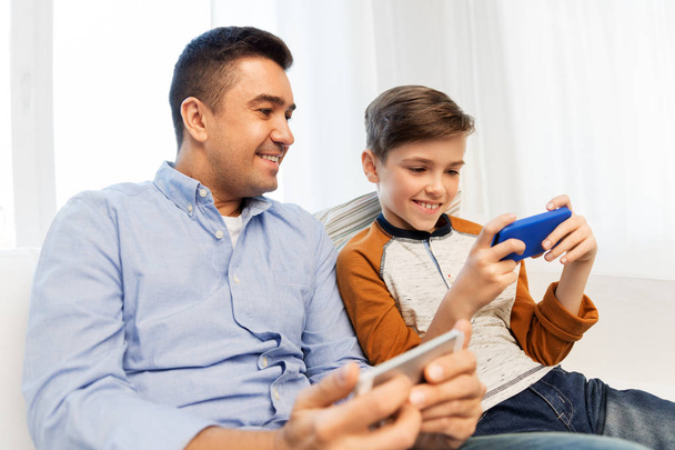 happy father and son with smartphones at home - Foto, Bild