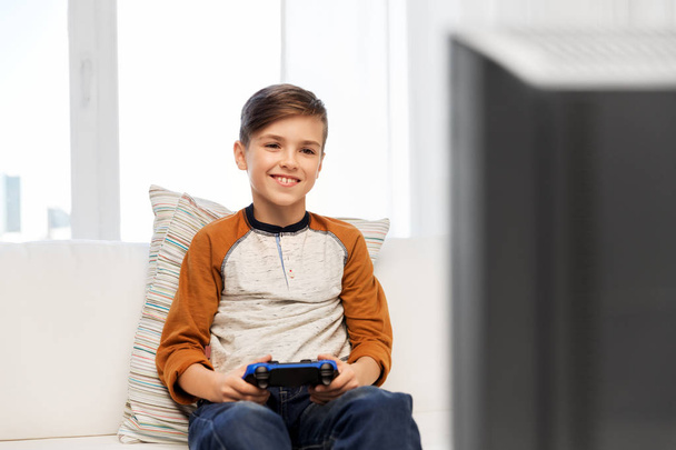 happy boy with gamepad playing video game at home - Foto, afbeelding
