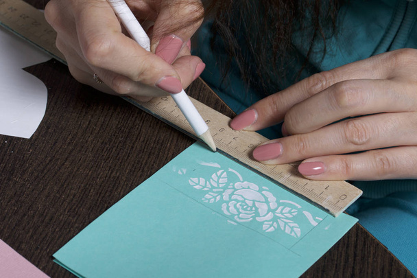 Making greeting cards from paper, cardboard and tape. Woman artisan makes a markup with a pencil. - Zdjęcie, obraz