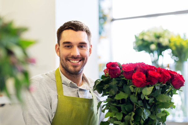 florist or seller with red roses at flower shop - Foto, Imagen