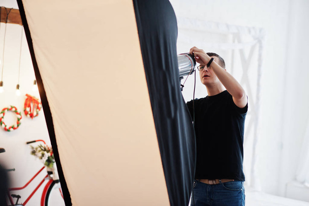 Photographer adjusts the flash light on studio.  - Фото, изображение