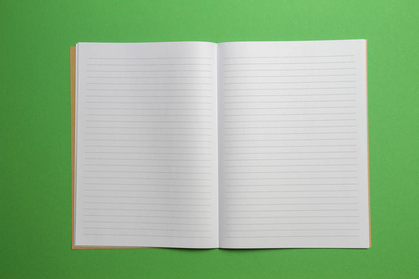 Vazio abriu caderno listrado em fundo verde. Vista superior
 - Foto, Imagem