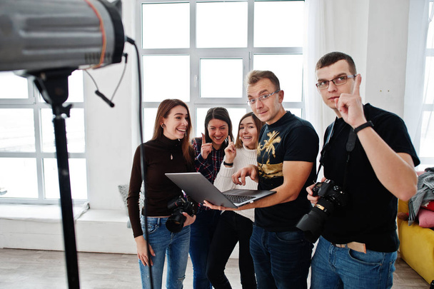 Photographer explaining about the shot to his team in the studio and looking on laptop. Talking to his assistants holding a camera during a photo shoot. Teamwork and brainstorm. - Photo, image
