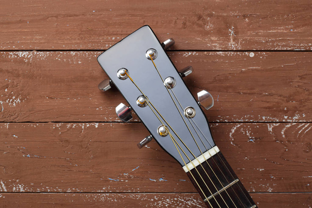 Μουσικό όργανο - headstock peghead μαύρο ακουστική κιθάρα σε ένα ξύλο παρασκήνιο. - Φωτογραφία, εικόνα