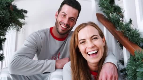 video van de Kaukasische man en vrouw thuis op trappen ingericht voor kerstavond  - Video