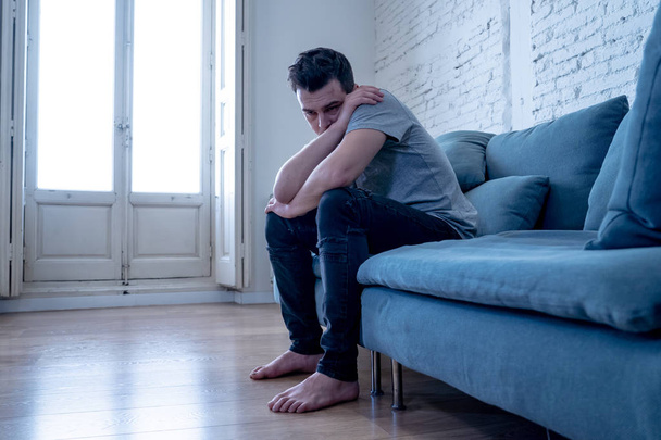 Portrait of young man felling depressed and desperate crying alone in sofa home suffering emotional pain and unhappiness. In People Broken heart, Bullying Depression and Mental health issues concept. - Foto, immagini