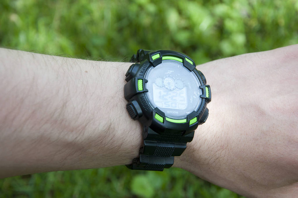 Час це життя. Цифровий годинник на чоловічій руці. Розумний годинник на природному тлі. Управління часом і точність. Розумний годинник з великим екраном. Фітнес-годинник для активного відпочинку. Сучасний цифровий гаджет
. - Фото, зображення