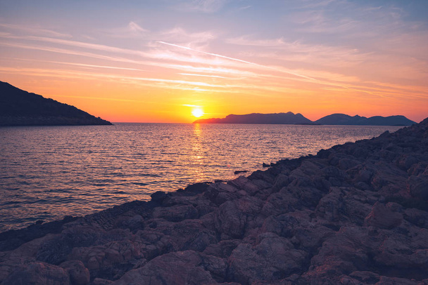 Amazing zonsondergang over de Middellandse Zee in de buurt van de stad van Kas, Turkije - reizen langs Lycische weg. Oranje zon in paars zee boven eilanden aan de horizon. Groothoek, vintage afbeelding. - Foto, afbeelding