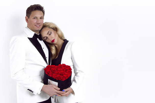 Feliz casal bonito posando no fundo branco e segurando caixa de flores com coração vermelho. Dia dos Namorados, casamento - Imagem
 - Foto, Imagem